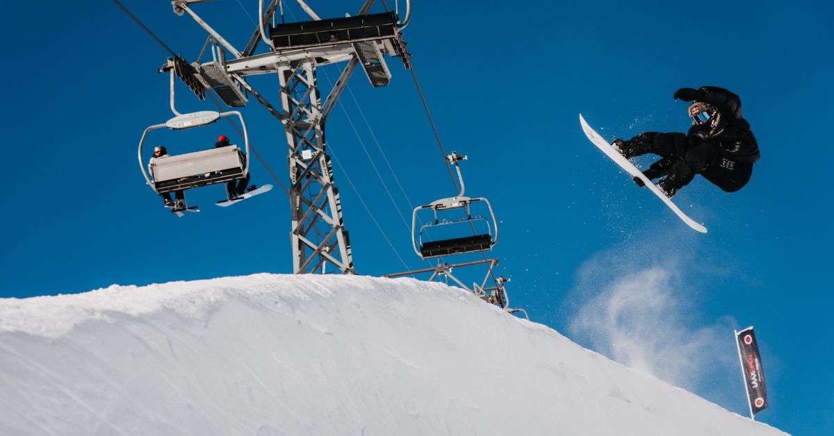 Ragazzo che salta con tavola da snowboard e abbigliamento da snowboard
